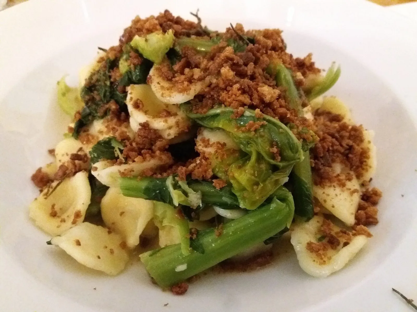Piatto bianco di orecchiette con cime di rapa verdi e mollica di pane tostata sparsa sopra